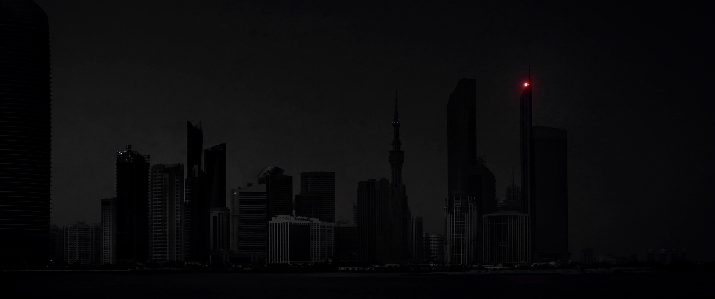 modernist skyline at night with a single red beacon