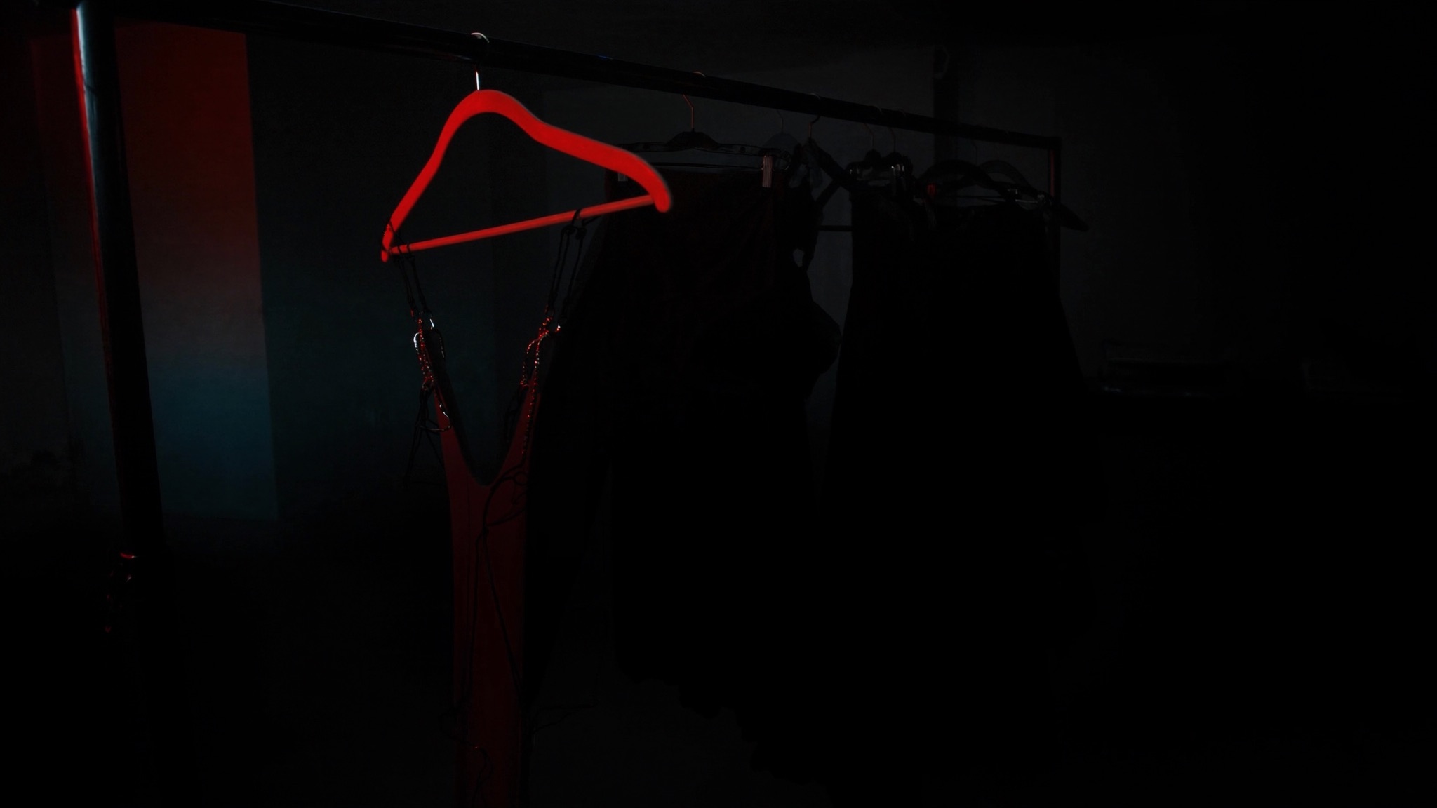 garment rail silhouettes with a single red-lit hanger